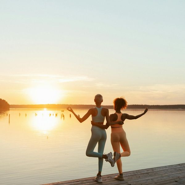 Person stretching gently outdoors during sunrise.